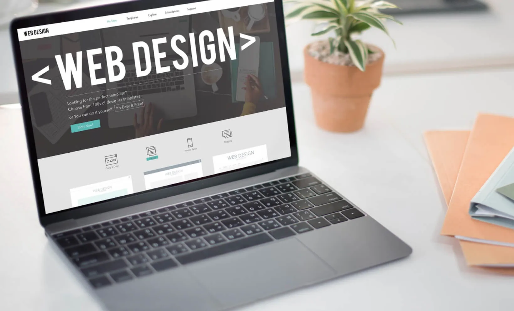 Laptop showing ‘WEB DESIGN’ site builder on a desk.