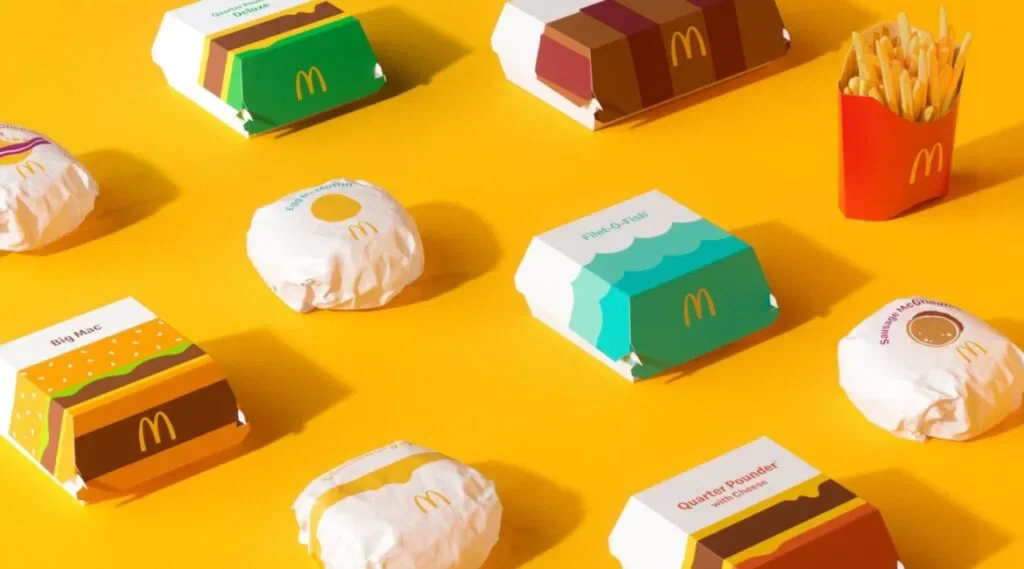 McDonald's packaging on yellow background showcasing burgers, fries, and vibrant box designs.