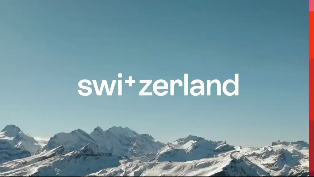 Switzerland Tourism's 2024 rebranding logo "swi+zerland" over a scenic snowy mountain backdrop.