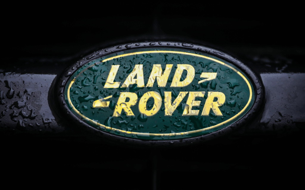 Land Rover badge with yellow text on green oval, covered in water droplets.