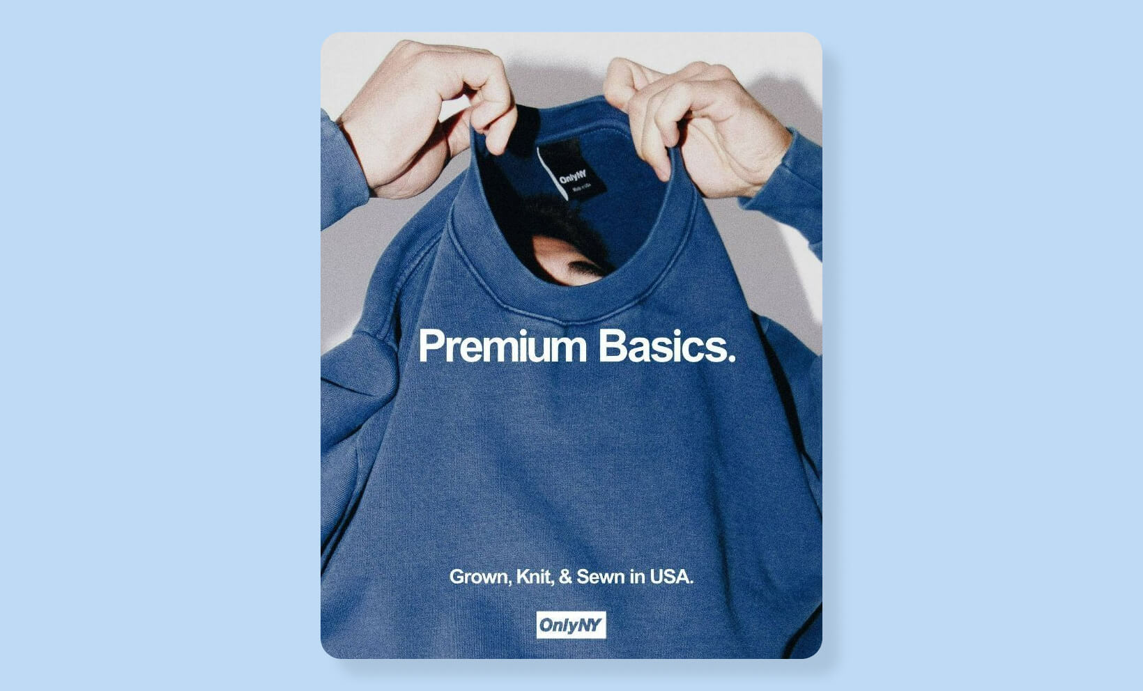 Person holding a blue Only NY sweatshirt featuring the slogan “Premium Basics” and made-in-USA branding